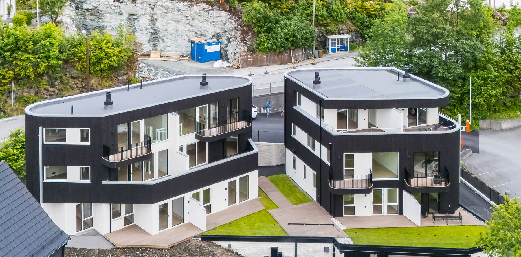 Dronebilde av to moderne tomannsboliger med svart kledning i Paradis, Bergen