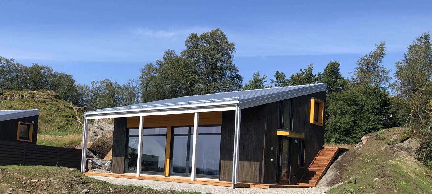 Moderne hytte med overbygd terrasse og store vinduer
