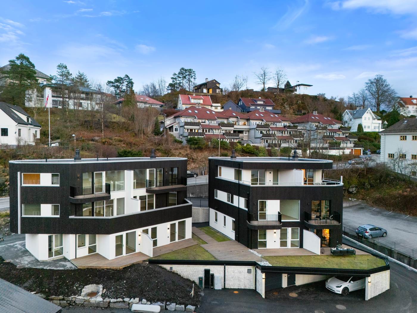 To tomannsboliger i svart og hvitt på en skrånende tomt i Paradis